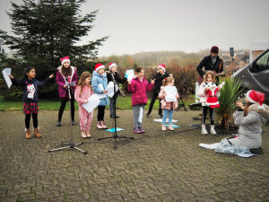 A group of children singing in front of a Christmas tree