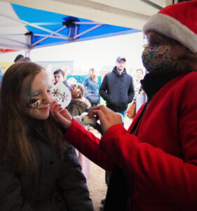 A woman applies face stickers to a child in the process of face painting