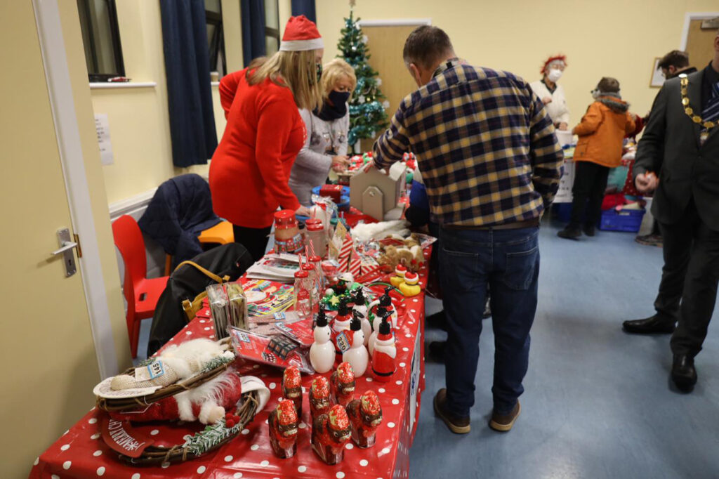 A group of people around a table covered in Christmas gifts.