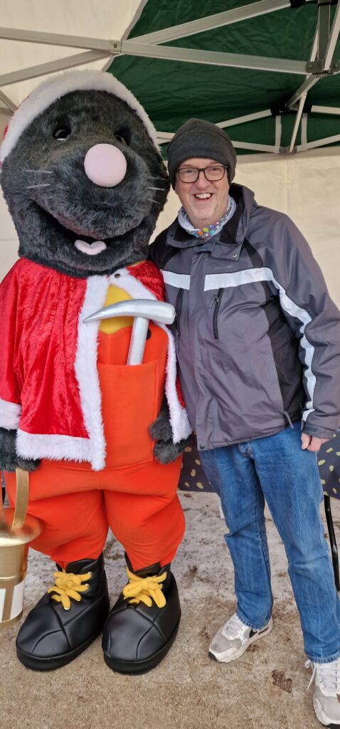 A man leans in for a photograph with Mawley the mole mascot