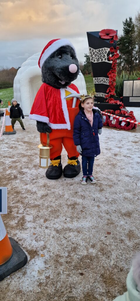 Mawley the mole mascot stands besides a young girl