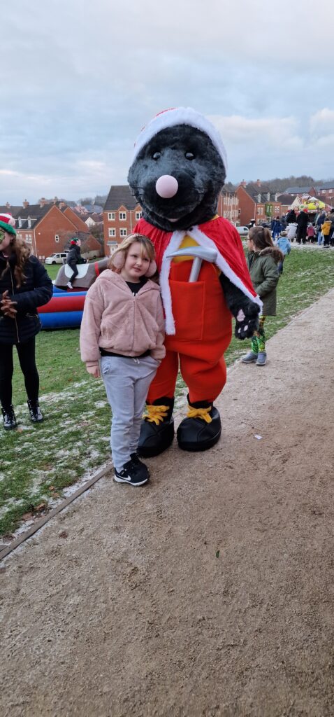 Mawley the mole mascot hugs a child as they pose for the camera