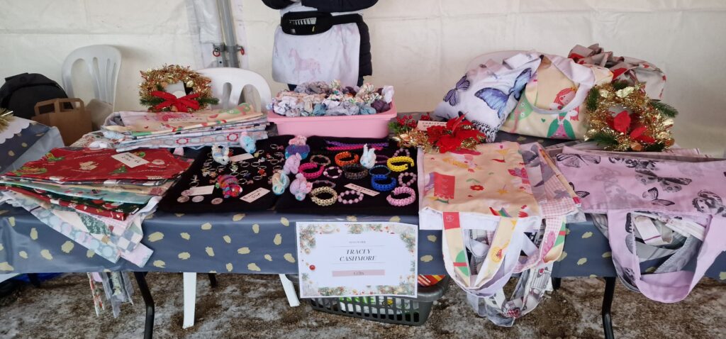 A table covered in multi-coloured jewellery and tote bags