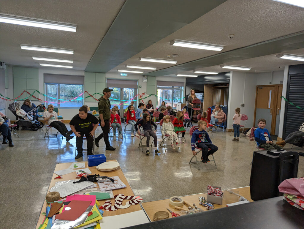 A large group of children sitting on chairs in a hall