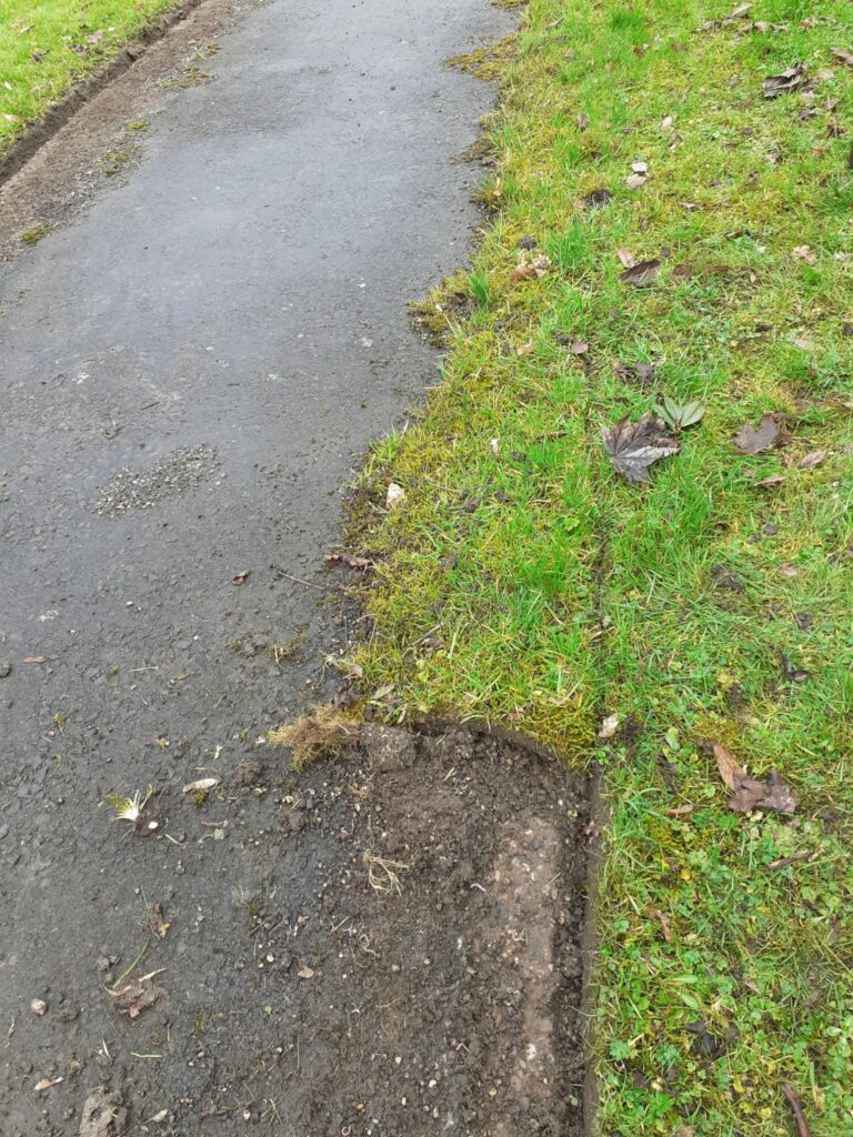 A footpath with edges partly-covered in grass, and partly freshly-edged.