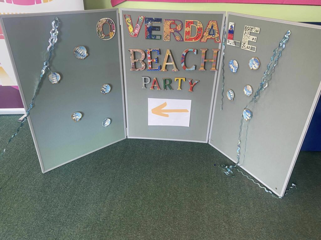 A display board with the words 'Overdale Beach Party' attached to it