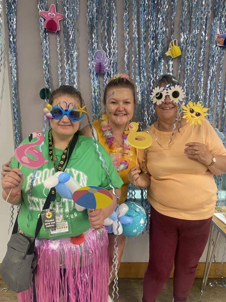 A group of three people wearing novelty classes. One is wearing a grass skirt