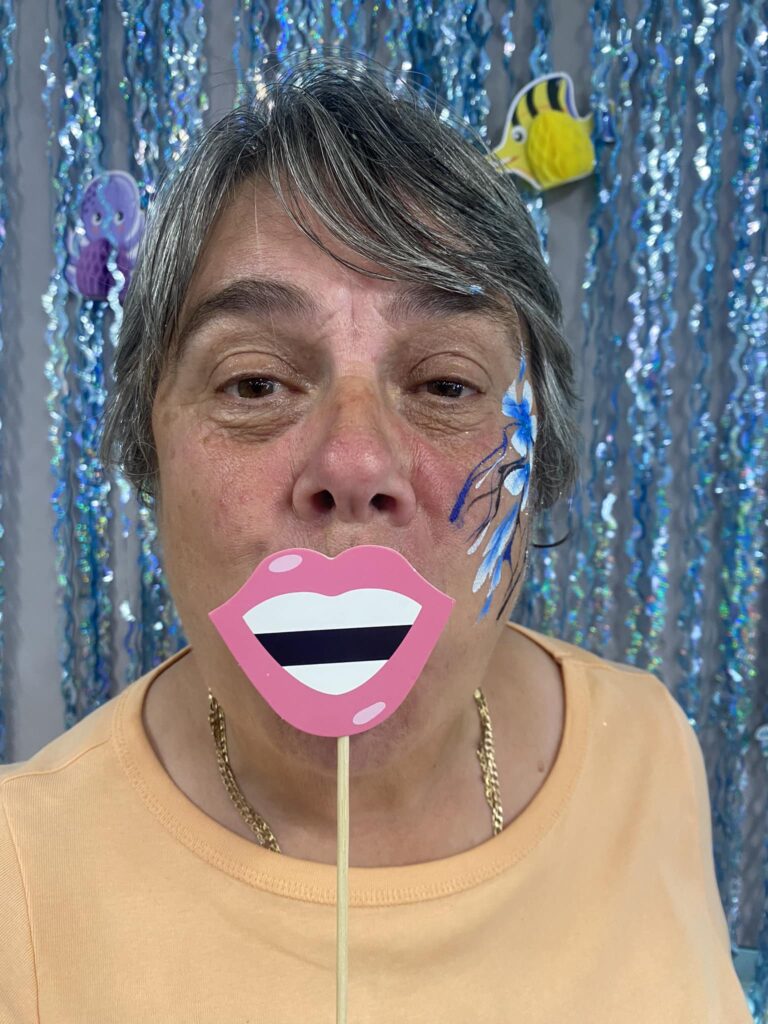 Someone holding up a fake mouth on a stick that's covering their own mouth
