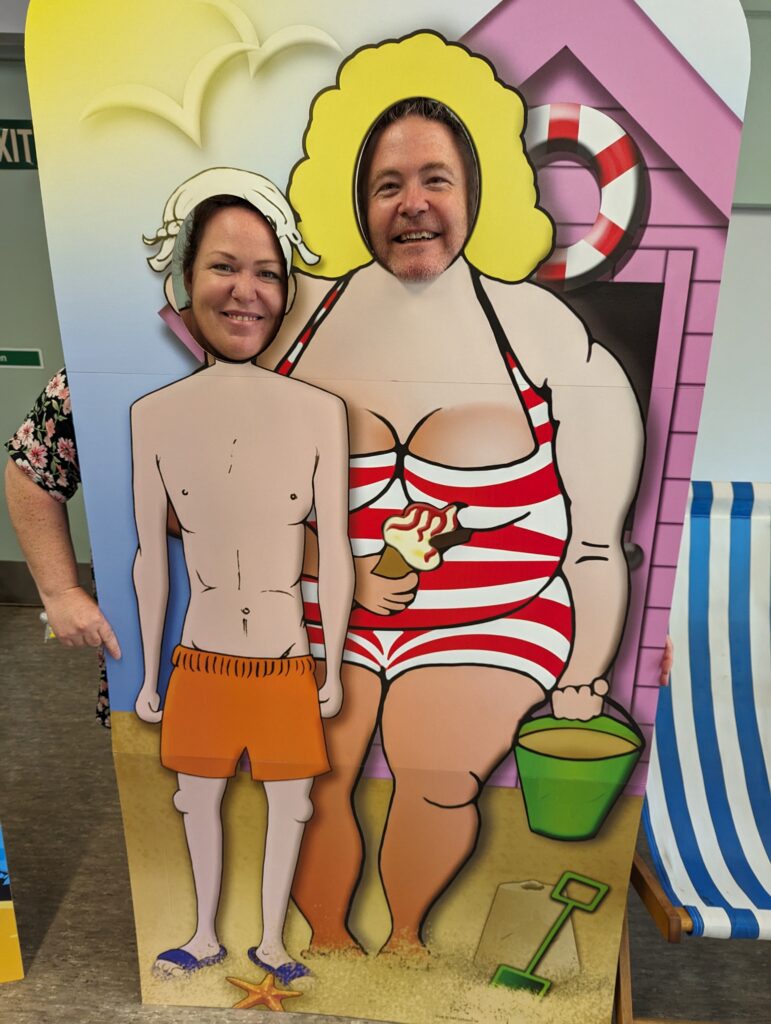 Two people hold their heads up behind a novelty photo frame