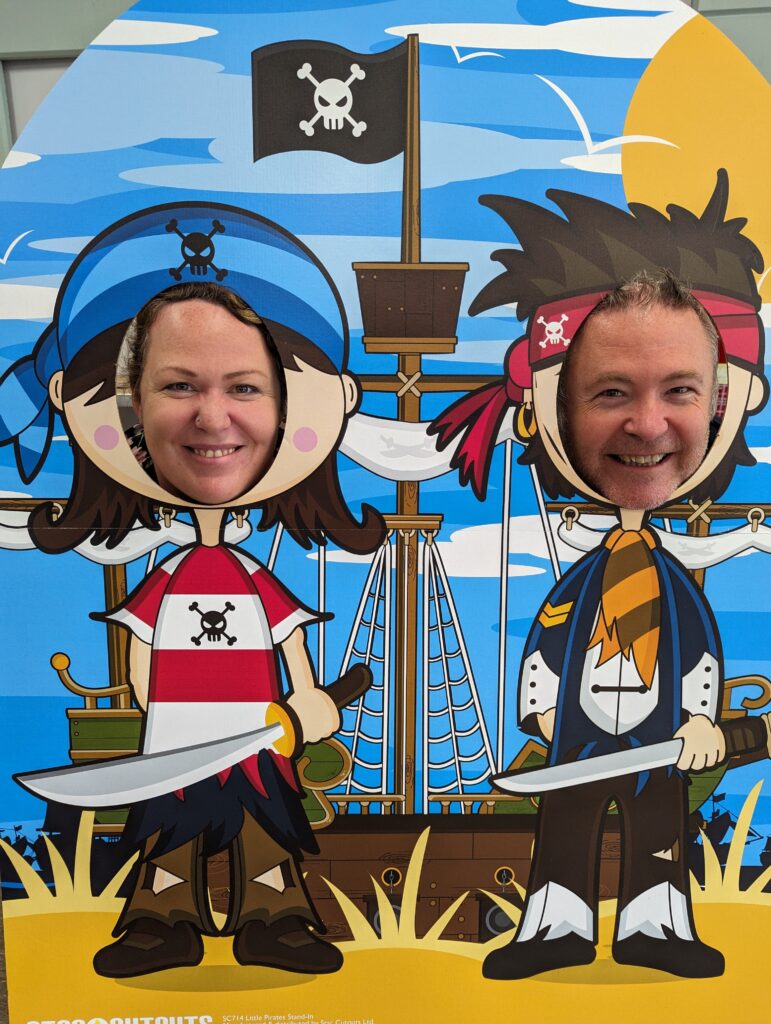 Two people hold their heads up behind a novelty photo frame