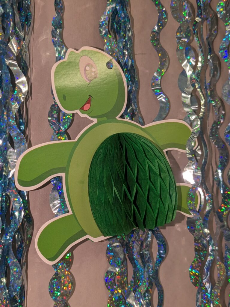 A cardboard cutout of a cartoon turtle, attached to sparkly drapes