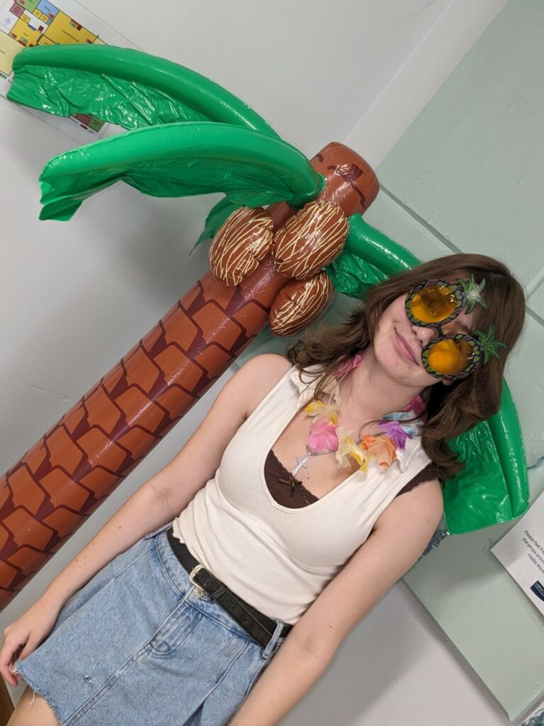 A child with novelty sunglasses standing next to an inflatable palm tree