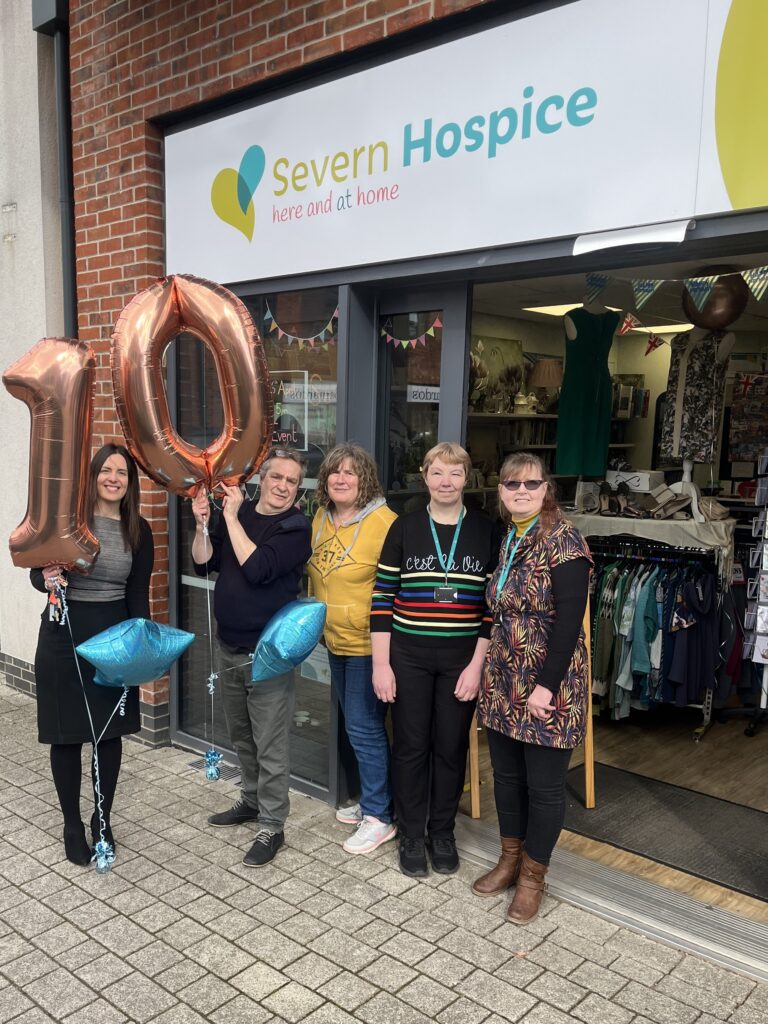 photo of 5 people standing outside a shop with balloons