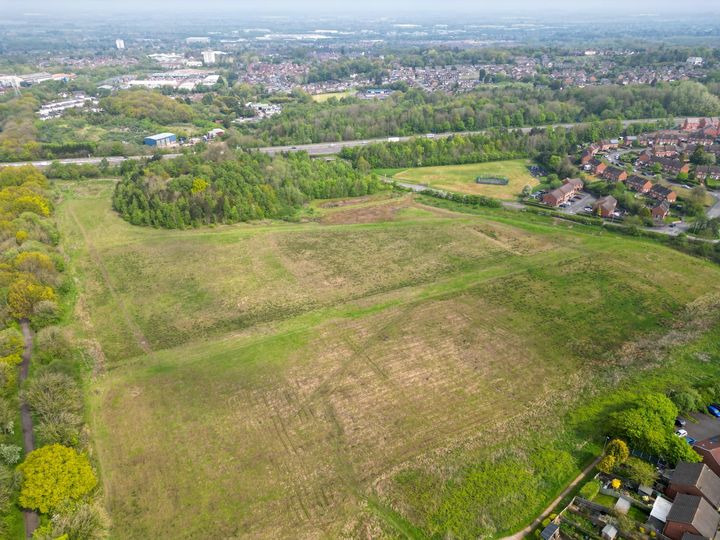 photo of the area, showing grassland, houses and trees.
