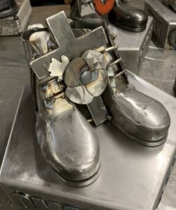a pair of steel boots, slightly parted with a cross and poppy placed in the middle